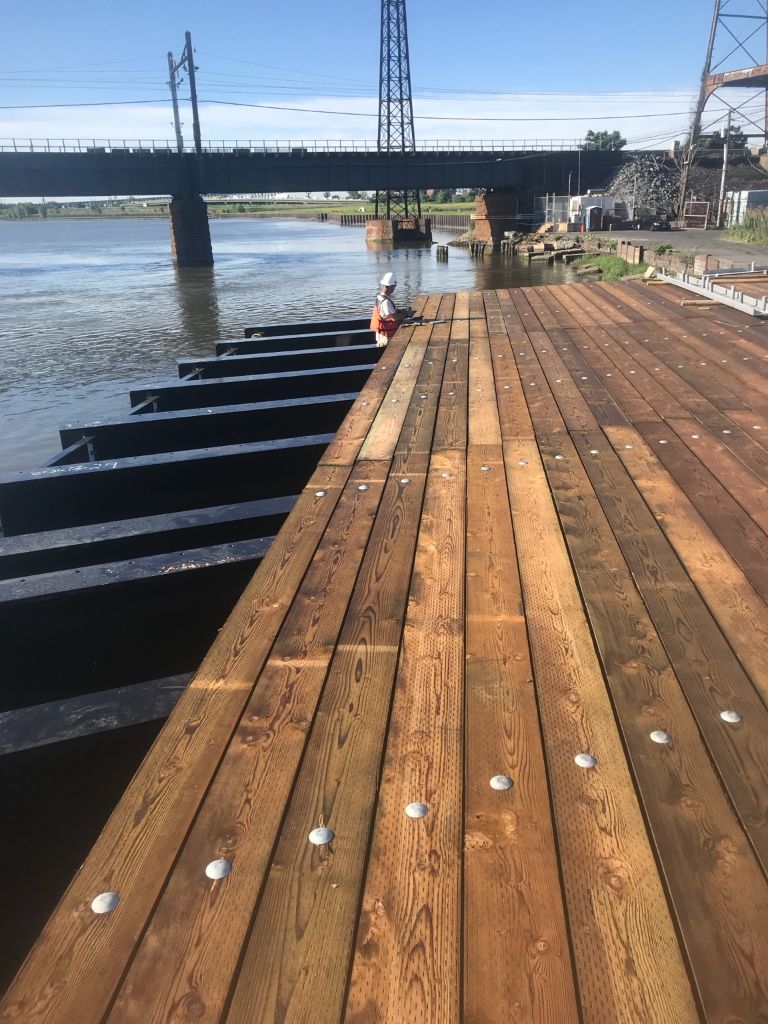 SubCon crew completing a newly constructed timber dock with steel substructure on a river waterway — marine construction